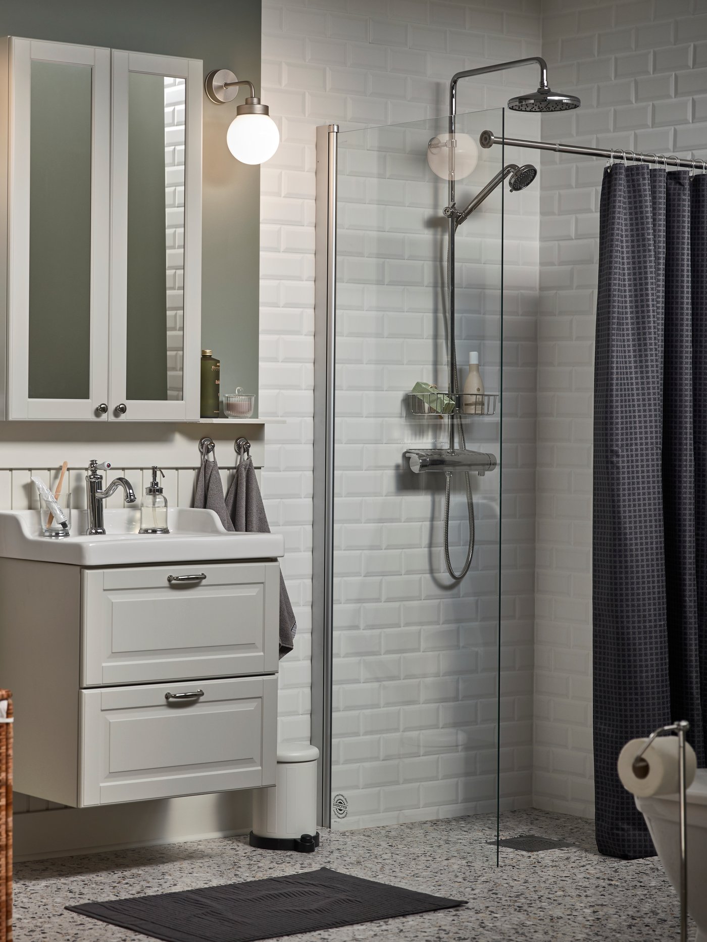 Bathroom with white subway tiles, chrome-plated shower set, grey shower curtain, white cabinet, and bathroom accessories.