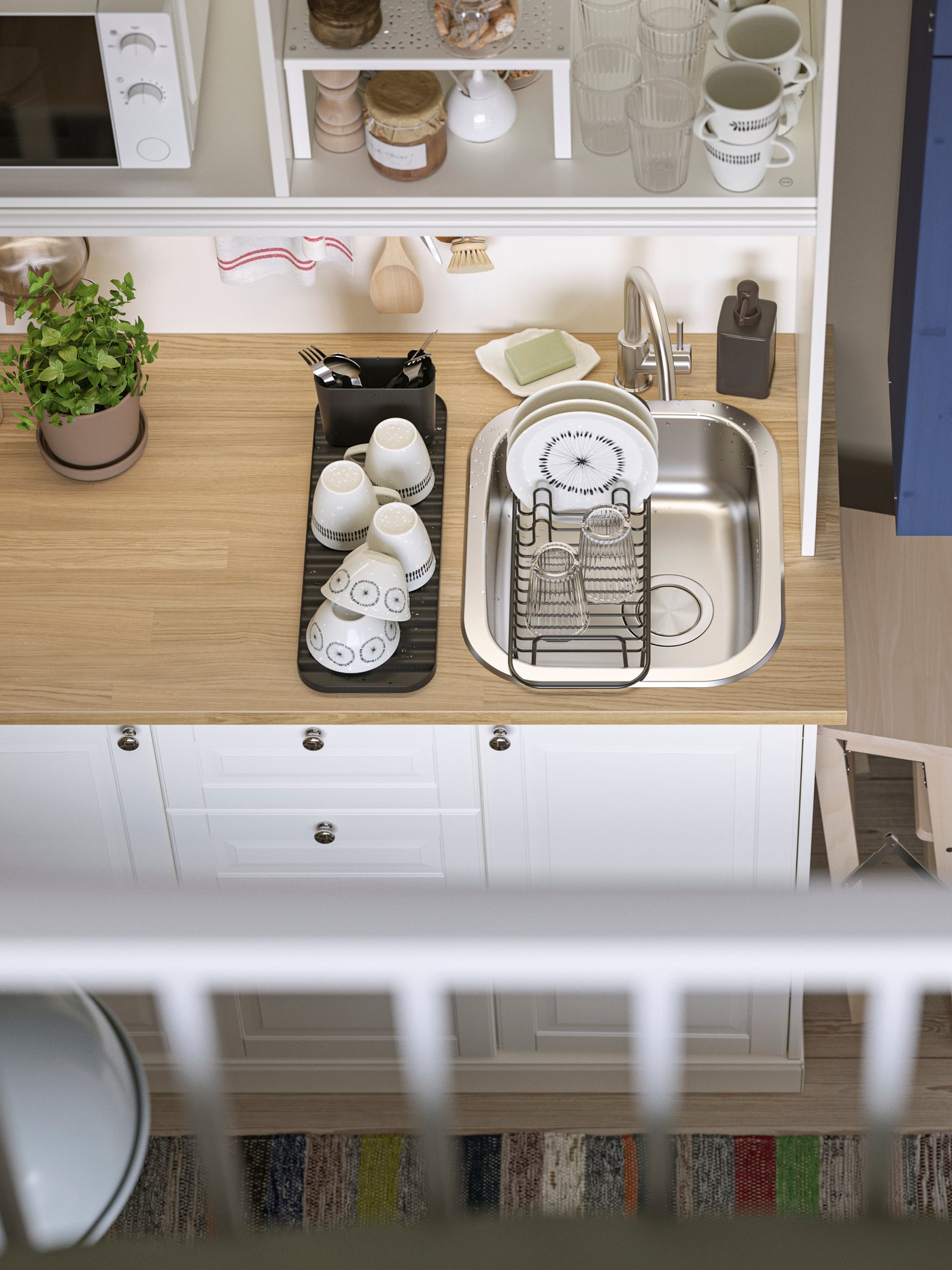 Ein Einzimmerapartment von oben mit Blick auf eine weiße ÖNNERUP Kochnische mit einem blauen IVAR Schrank und einem LAGAN Kühlschrank.