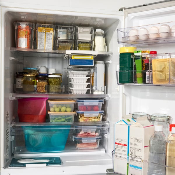 透明な容器やパック、瓶、ボトルに入ったさまざまな食品が整然と収納された冷蔵庫。卵、果物、野菜、乳製品、調味料などが見え、清潔で整理された冷蔵庫の様子を示しています。