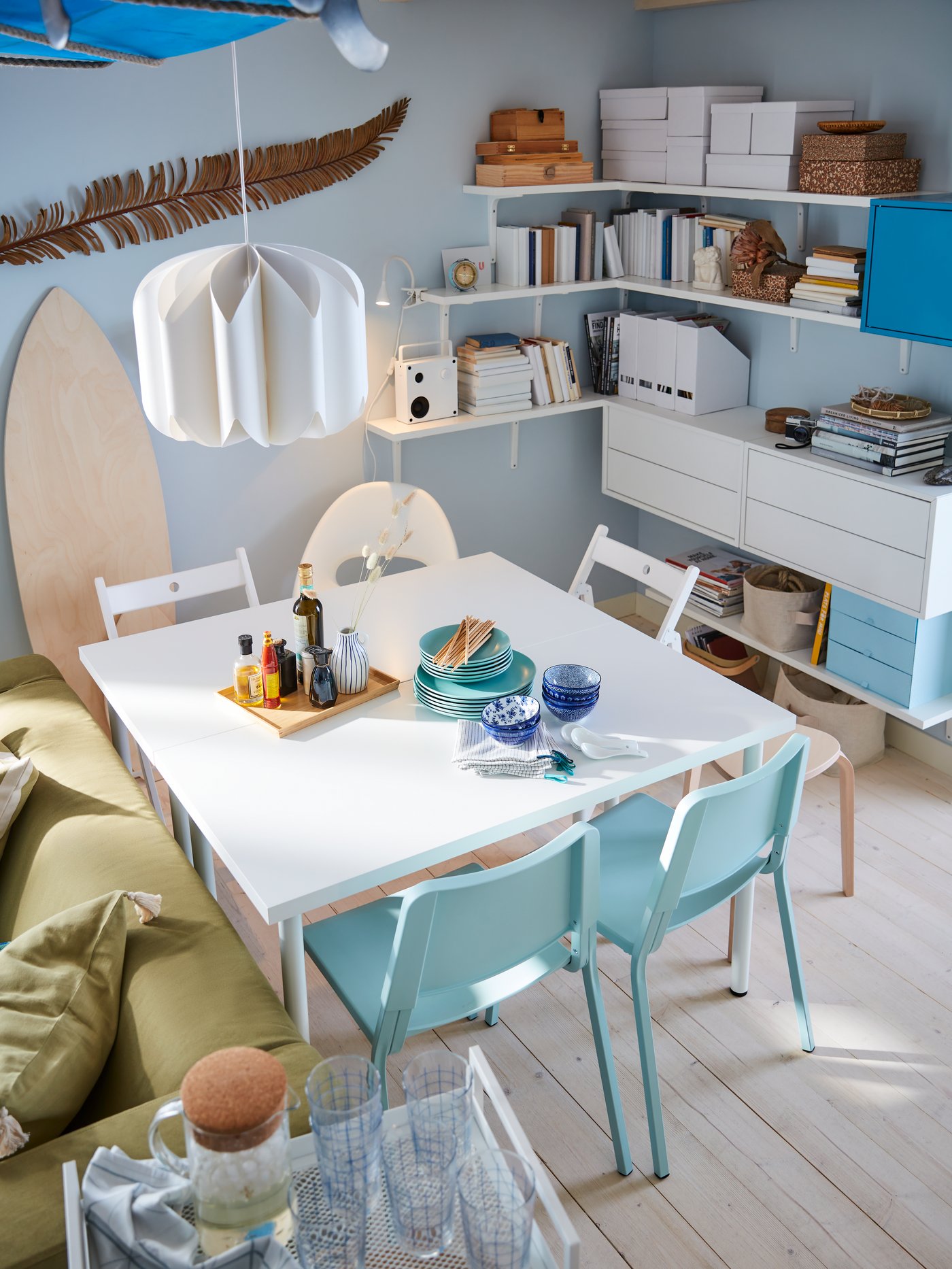 Zona de comedor con una mesa, una silla giratoria, una pantalla de lámpara, un carrito, sillas, armarios, archivadores, un altavoz y vajilla.