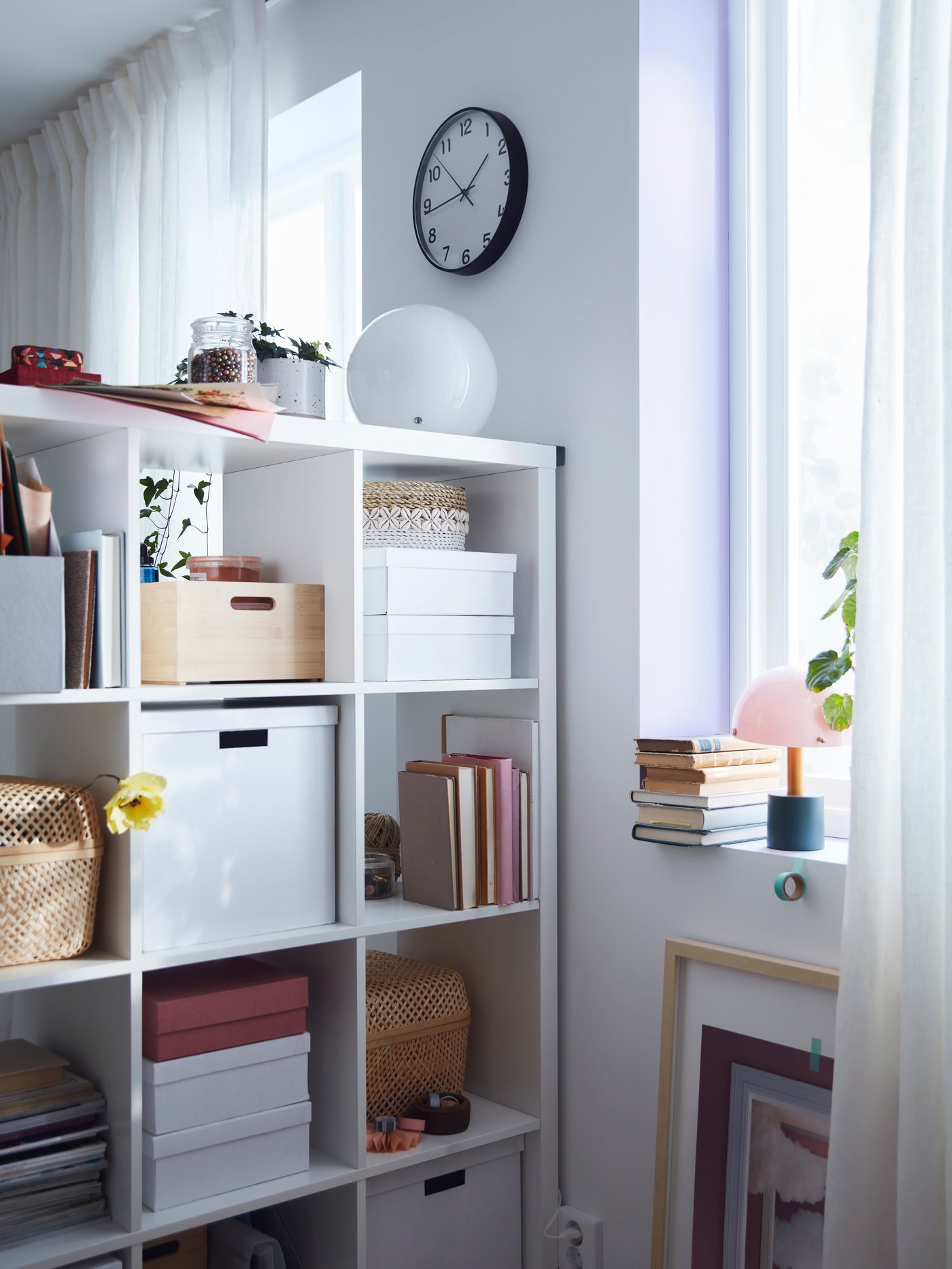 Eine weiße TJENA Box mit Deckel in einem KALLAX Regal in weiß.