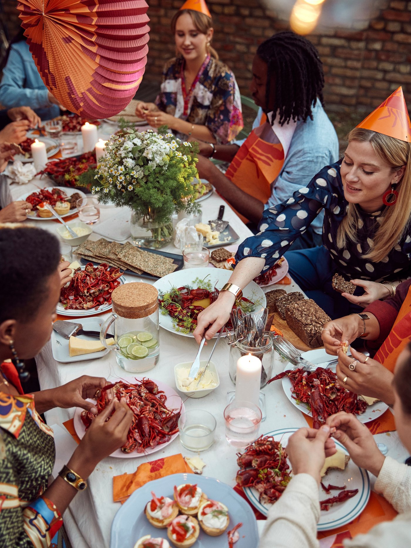 Personer som sitter runt ett bord och äter kräftor på en kräftskiva.