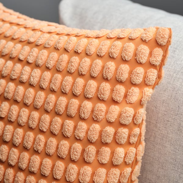 A light orange SVARTPOPPEL cushion cover