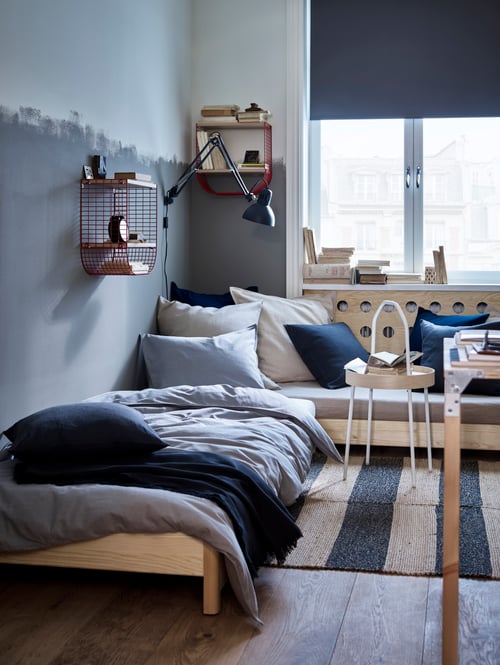 Bedroom with stackable bed, duvet cover, two pillowcases, side table, work lamp, rug, cellular blind, throw, cushion covers.