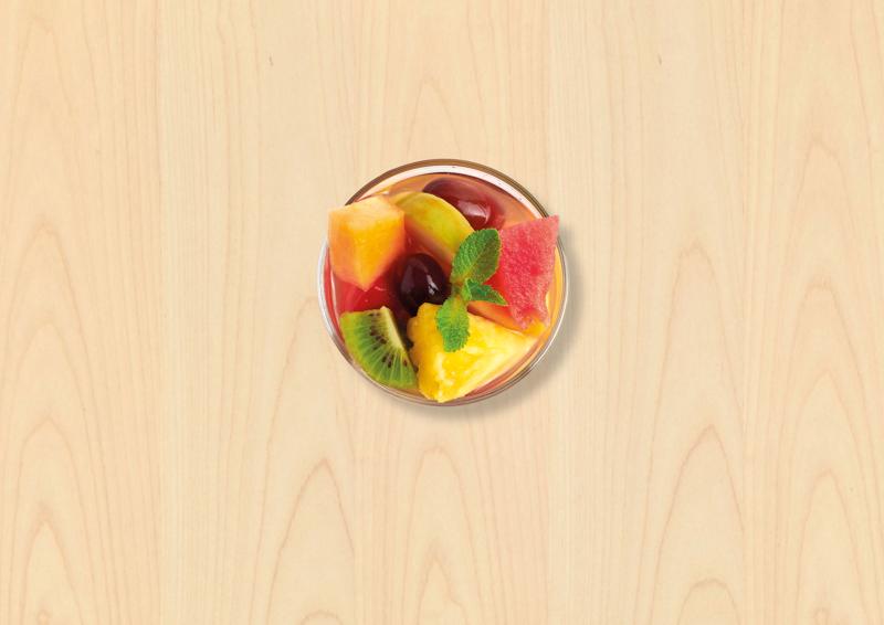 Bol transparent avec des fruits frais coupés en morceaux dedans, kiwi, pastèque, melon, raison, orange, pomme ...