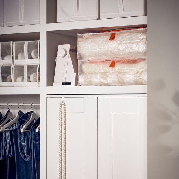 Two PÄRKLA storage cases lie on top of a shelf underneath which is a white BRIMNES wardrobe with 2 doors.