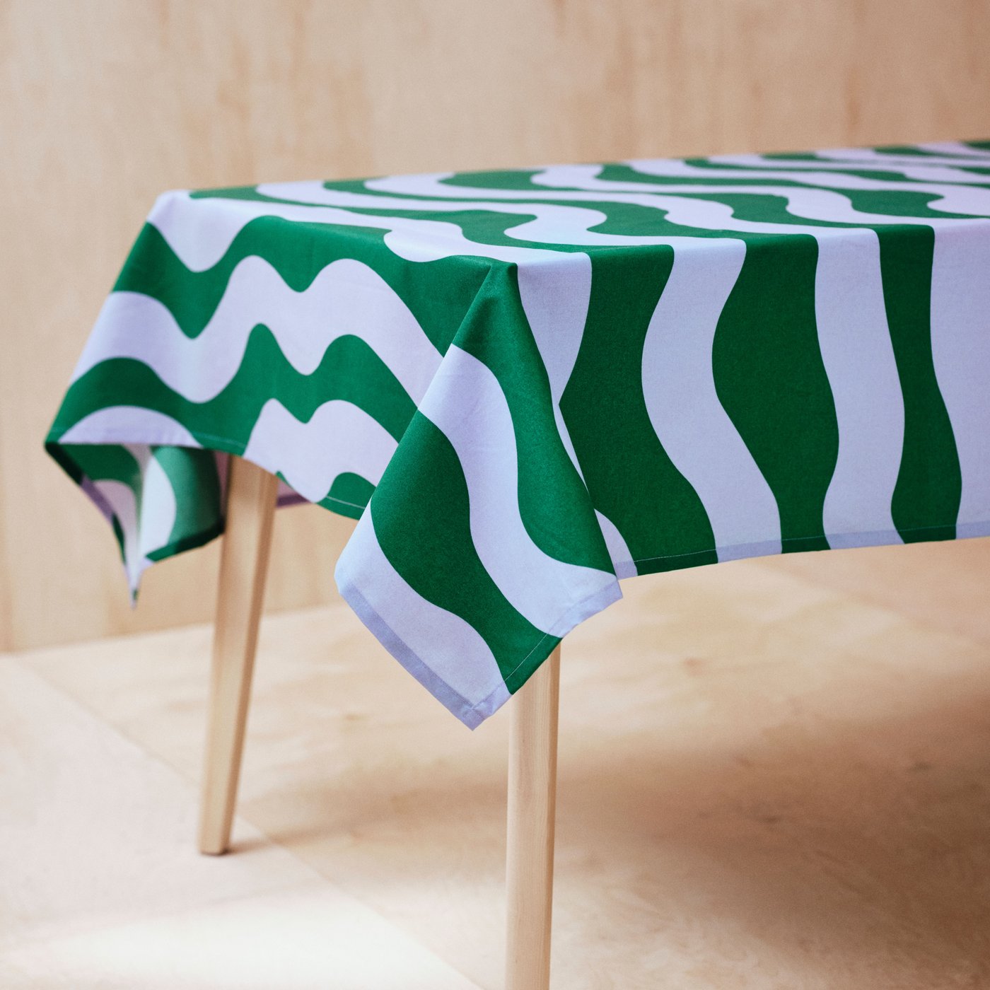 A wipeable TABBERAS tablecloth in green and lilac stripe-patterns is placed on a dining table.