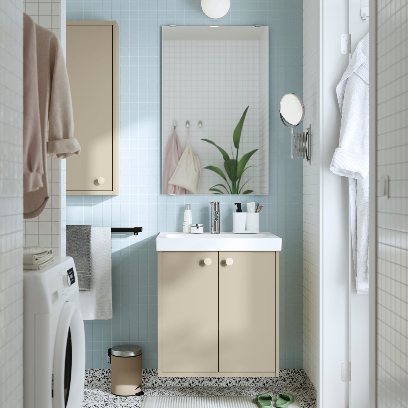Un bagno HAVBÄCK beige visto frontalmente completo di lavabo in ceramica bianco, mobile per lavabo con due ante, specchio verticale, con illuminazione a parete sferica sopra il pensile.