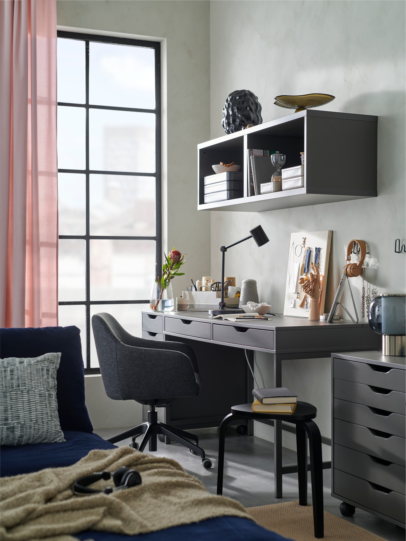 Un spațiu de lucru în camera de zi, cu un scaun de conferință TOSSBERG/LÅNGFJÄLL lângă un birou ALEX gri închis și unități de depozitare.