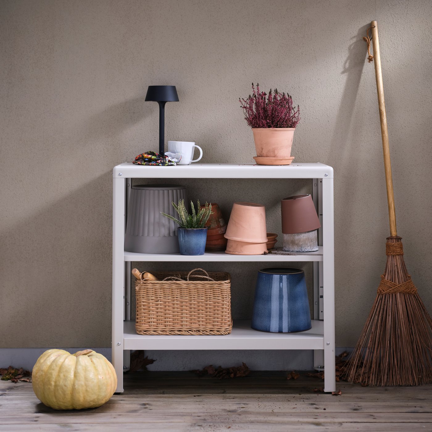 A KOLBJÖRN shelving unit holding many items, including a FJÄRILBUSKE plant pot and other plant pots, on a terrace.