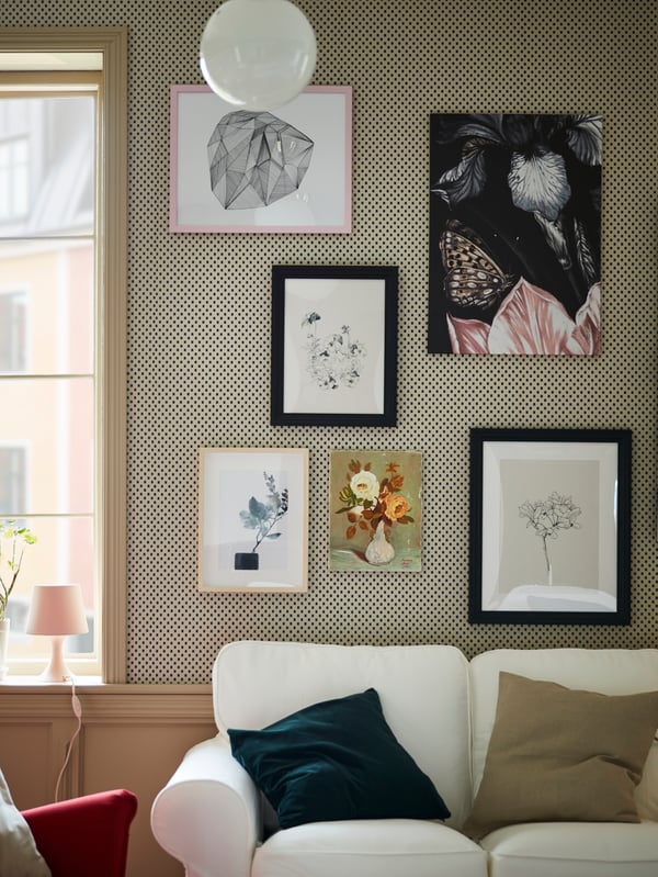 Black stained frames are combined with more frames to create a picture wall behind a white EKTORP sofa.