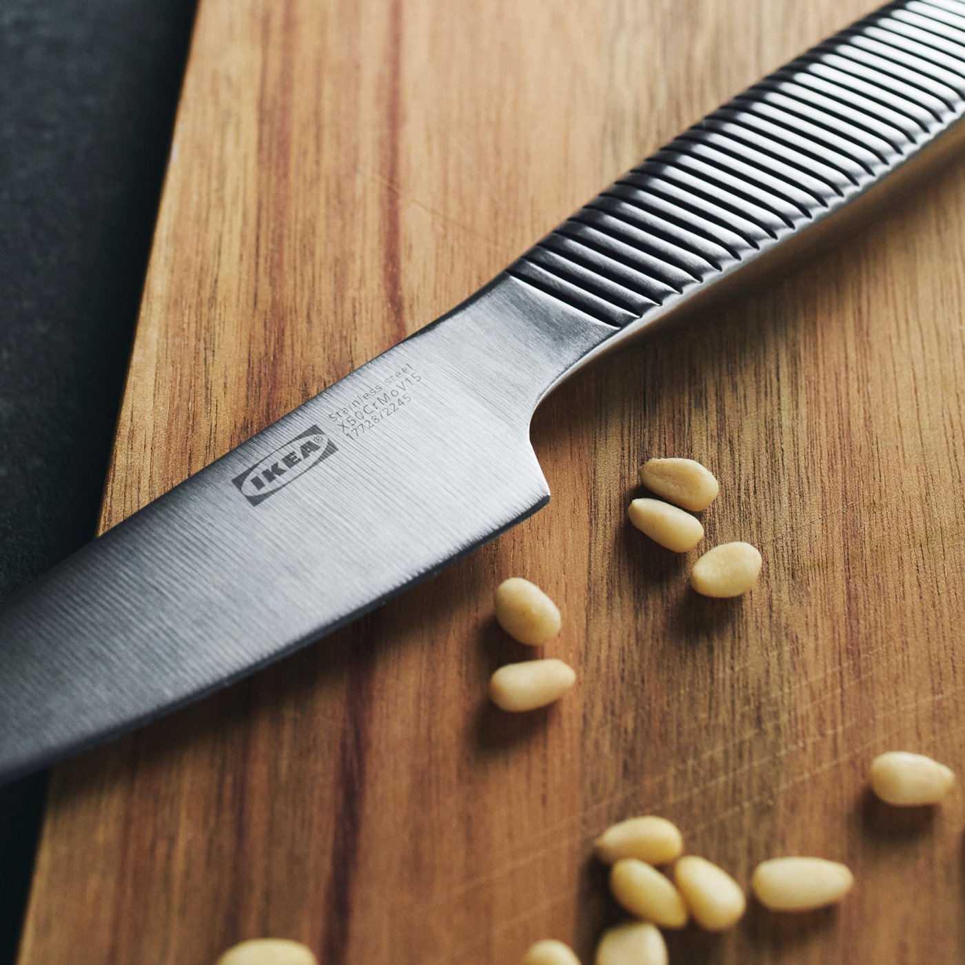 A close up of an IKEA 365+ knife on a wooden chopping board highlighting the knurled handle.