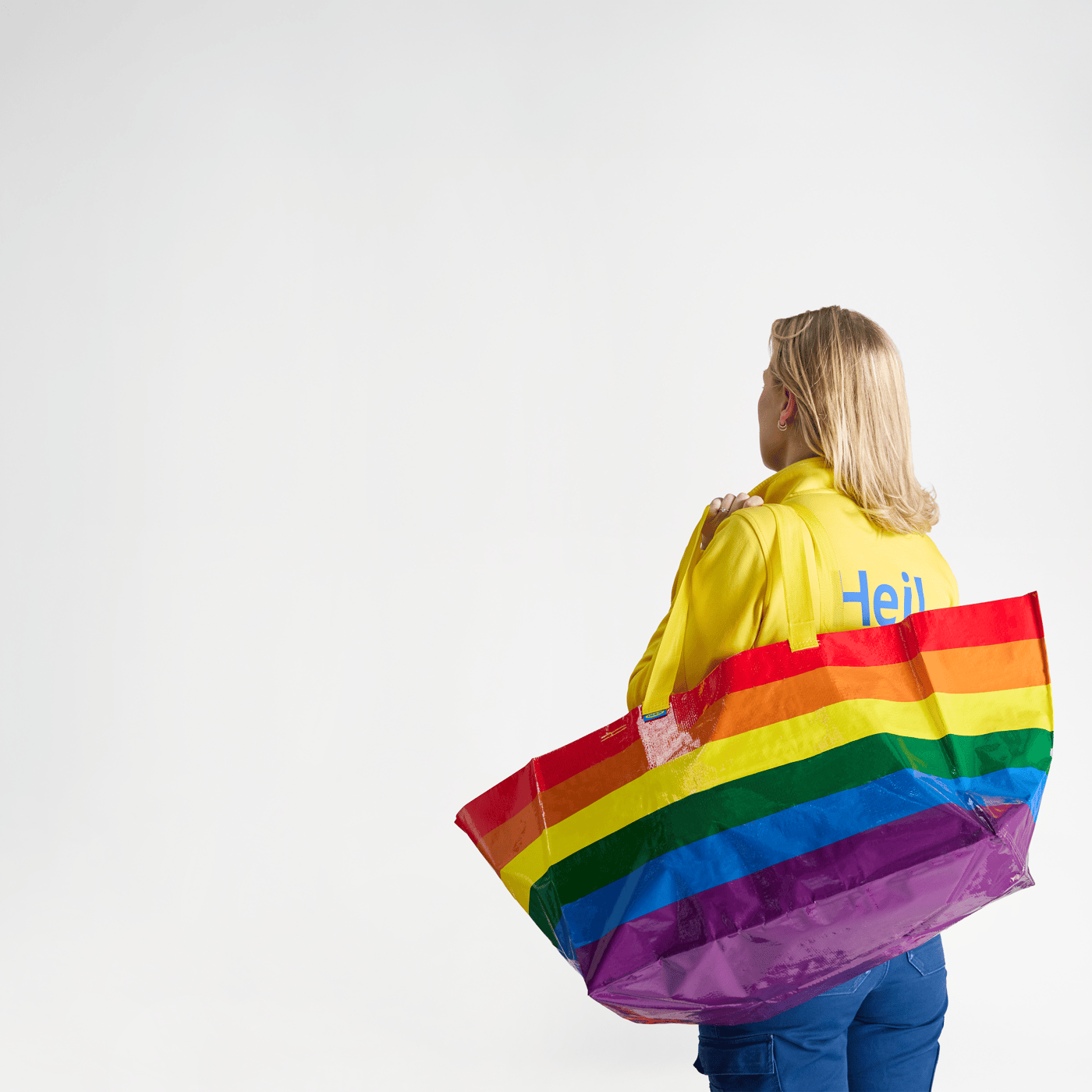 An IKEA employee carrying a rainbow STORSTOMMA bag.