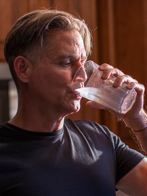 Man taking a sip of freshly squeezed lemon juice from a POKAL glass.