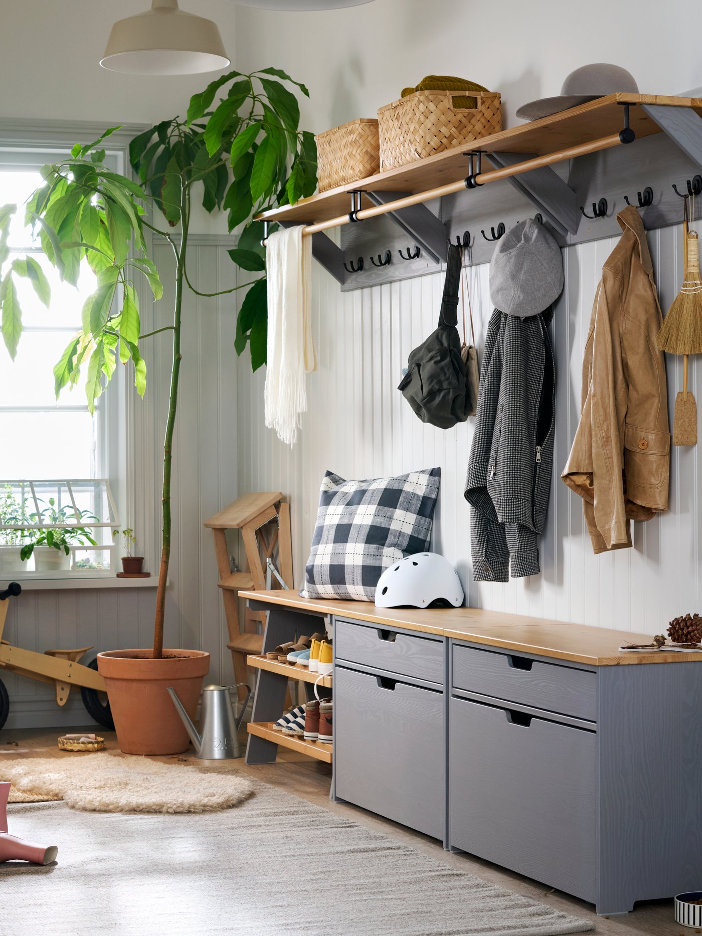 Atondo handia eta argitsua leiho batekin hondoan eta horma zuriekin. Horman zehar, kolore griseko eta zur-koloreko KALLSÖ biltegiratze-moduluak daude.