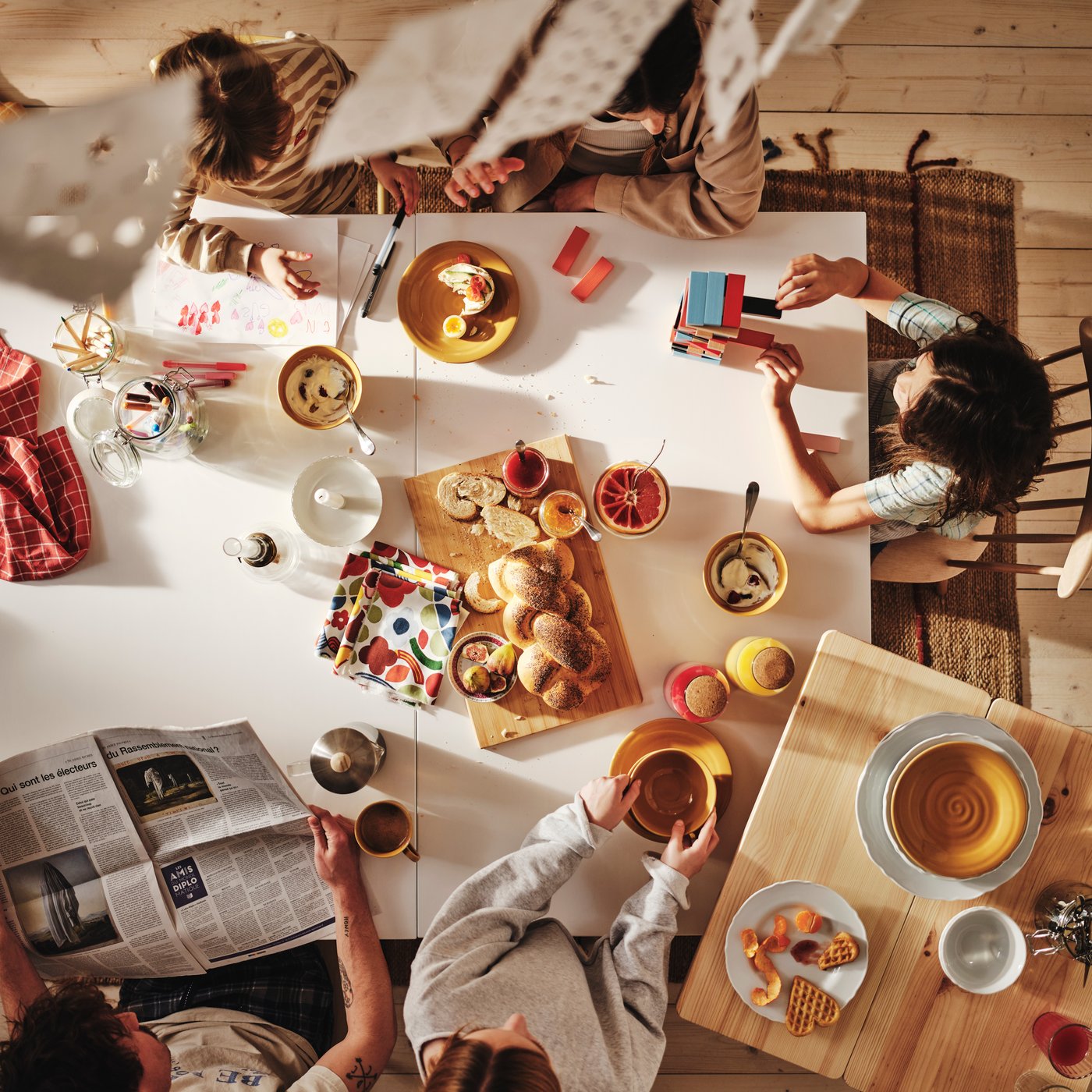 A family of five, viewed from above enjoying a leisurely breakfast around their large white dining table.