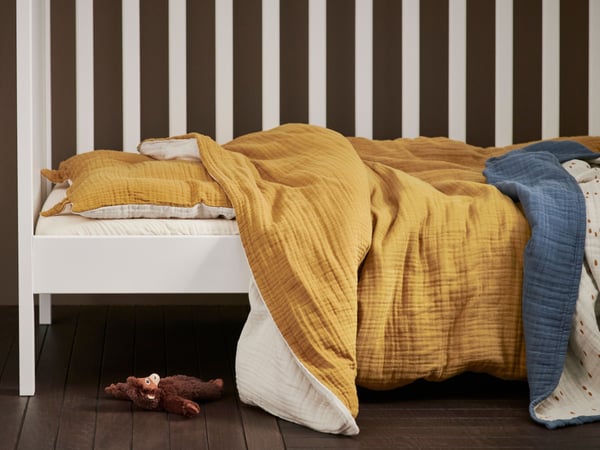 Une parure de lit 3 pièces GULDVÄVARE jaune foncé/beige pour le lit d'enfant dans la chambre d'enfant.