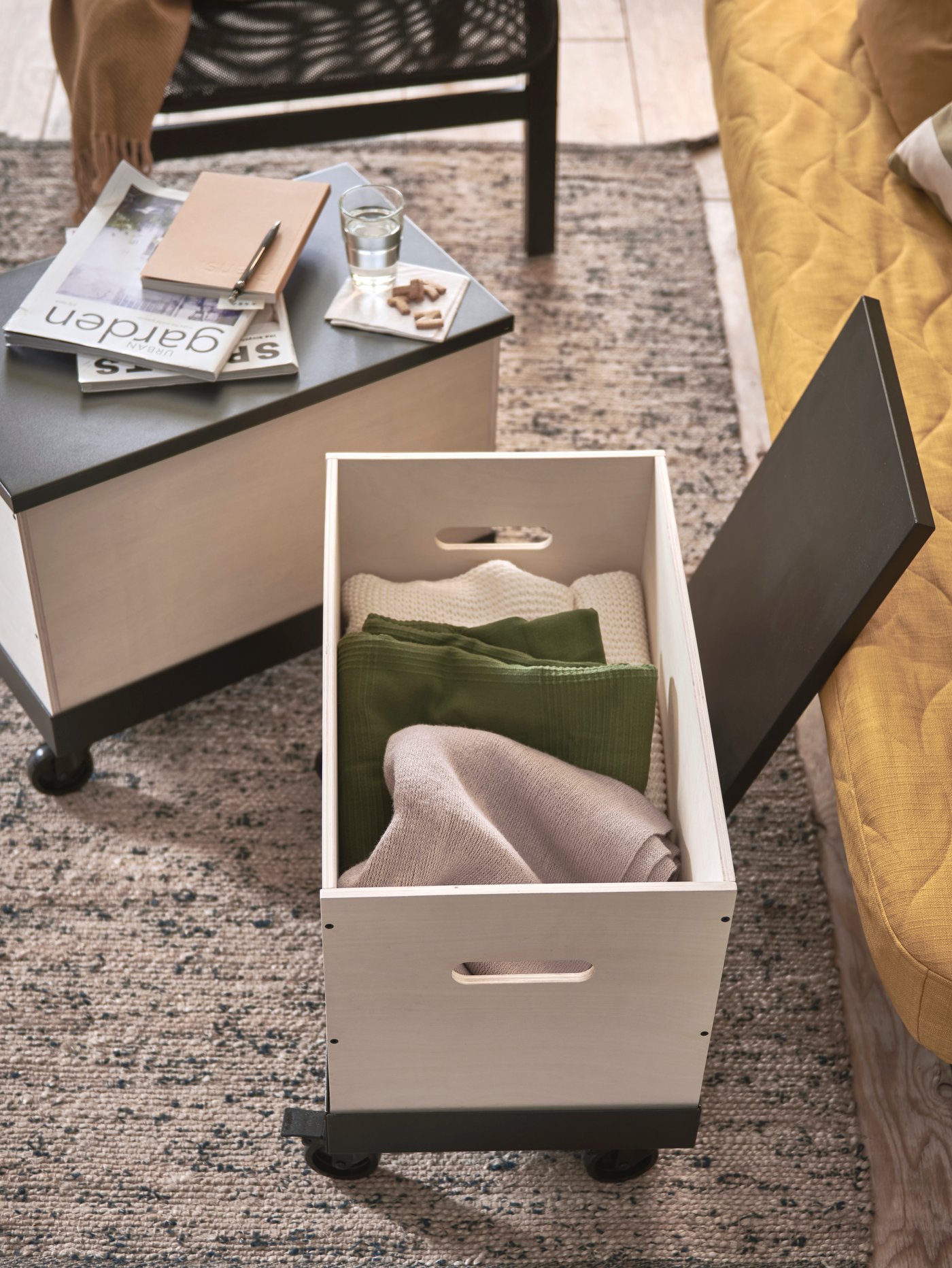 Deux tables basses/d’appoint sur roulettes faites en bouleau contreplaqué, avec l’une des tables ouvertes exposant les couvertures à l’intérieur.