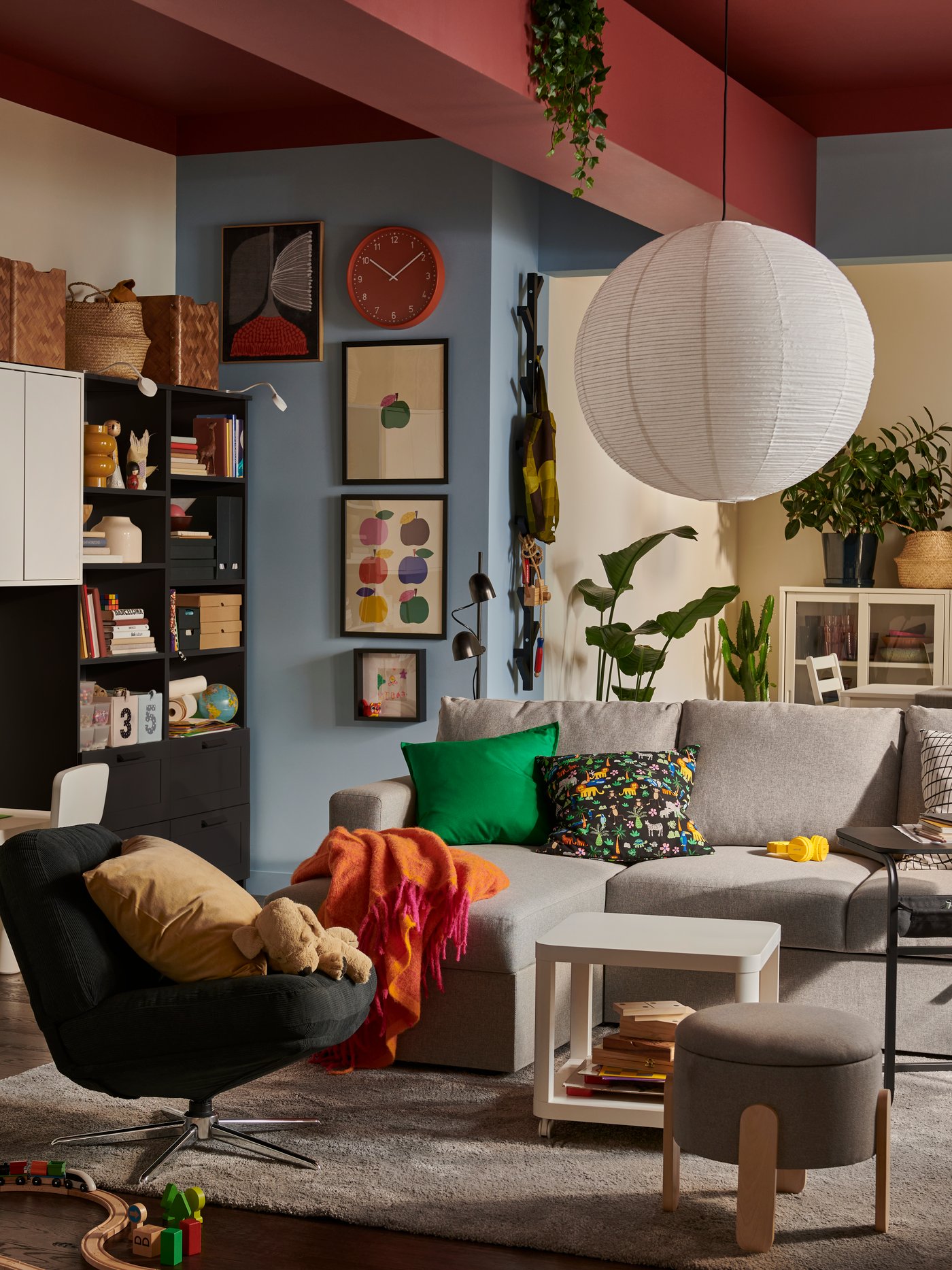 En ljus vardagsrumsmiljö med en beige/grå BÅRSLÖV tresits bäddsoffa med schäslong, omgiven av färgglad och lekfull inredning.