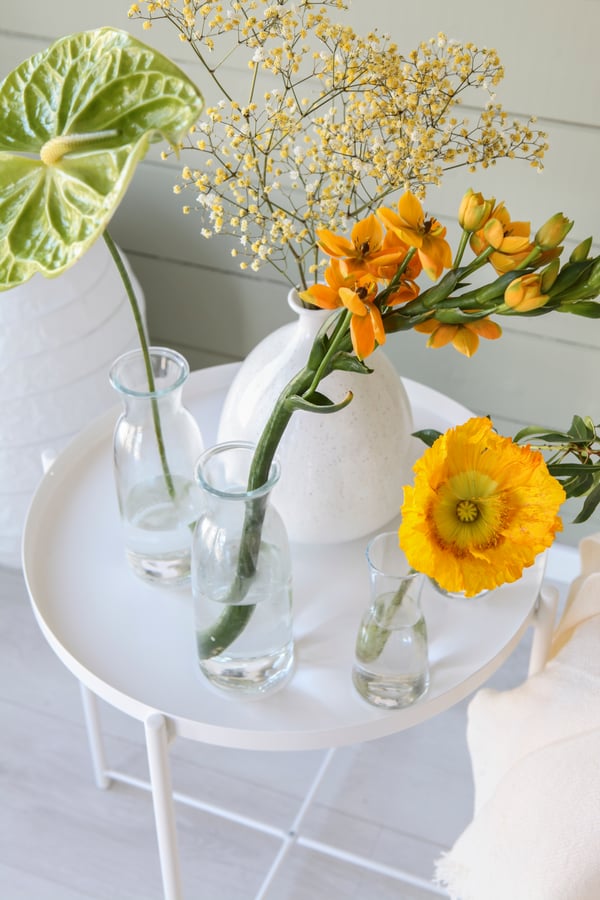 Friske blomster i gule toner i glasvaser.