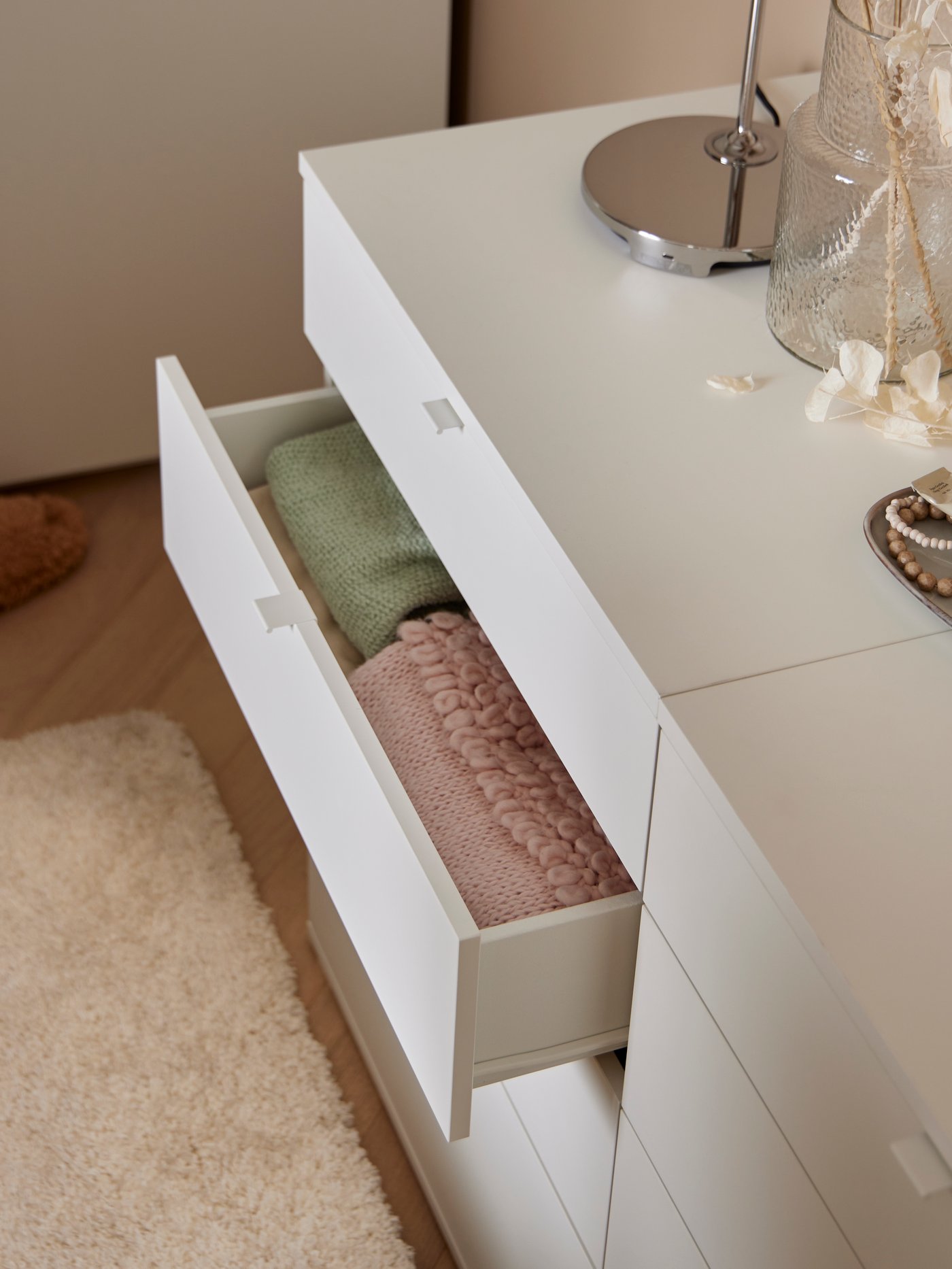 a open drawer of a white chest with clothes inside