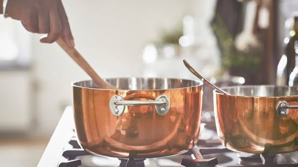 Una olla FINMAT de cobre/acero inoxidable con tapa.