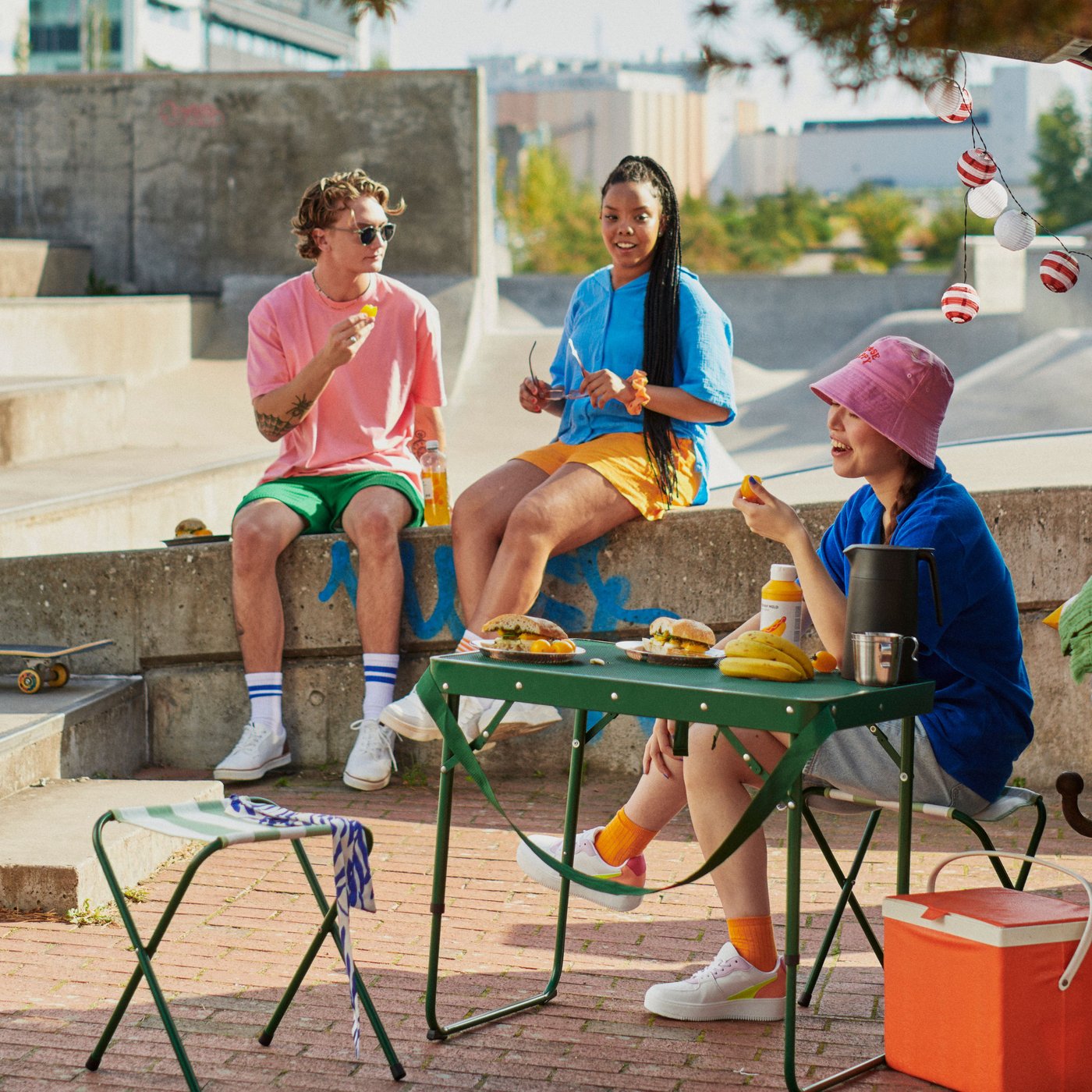Tres jóvenes disfrutando al aire libre en un juego de terraza portatil STRANDÖN 