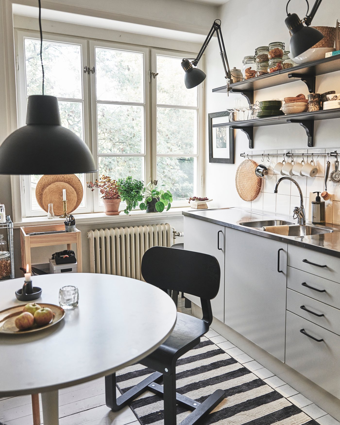 Ett vitt DOCKSTA bord under en svart lampa. I bakgrunden syns ett grått kök.