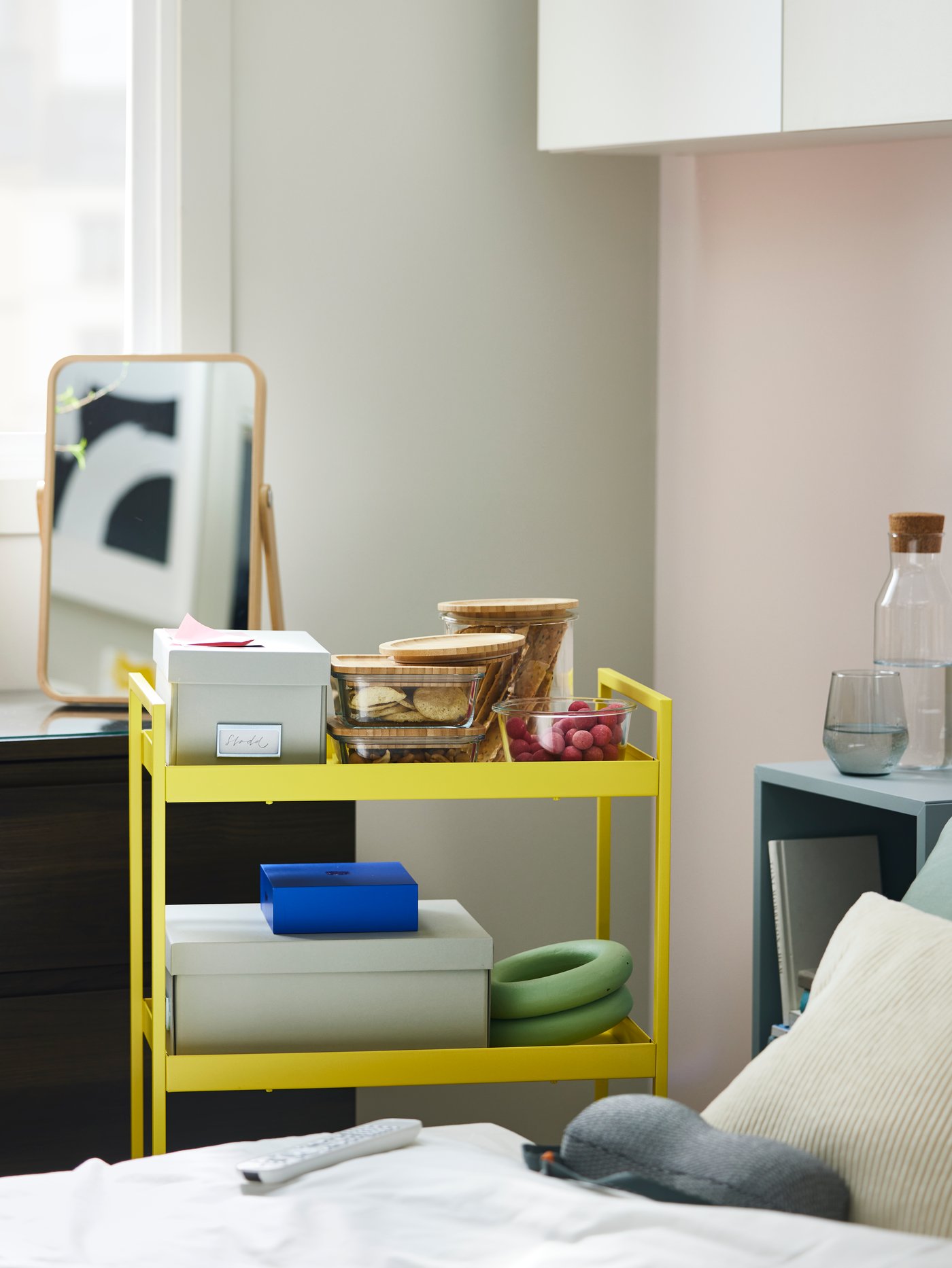 A yellow NISSAFORS trolley with various items on it including white boxes and IKEA 365+ food containers holding snacks.