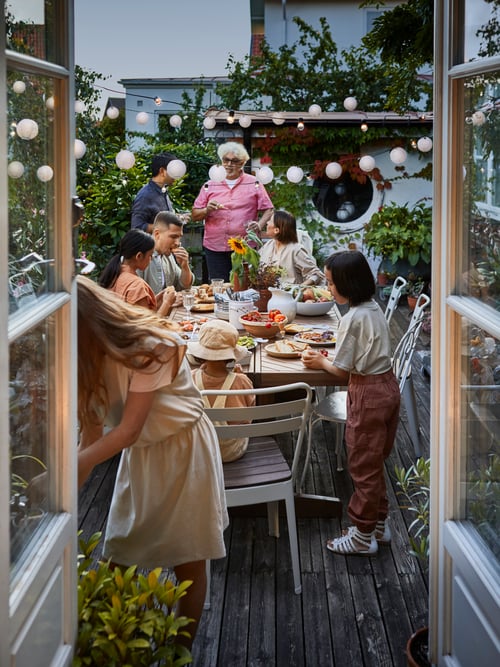 Friends and family enjoy a summer evening outdoors with their NORRMANSÖ table and chairs.