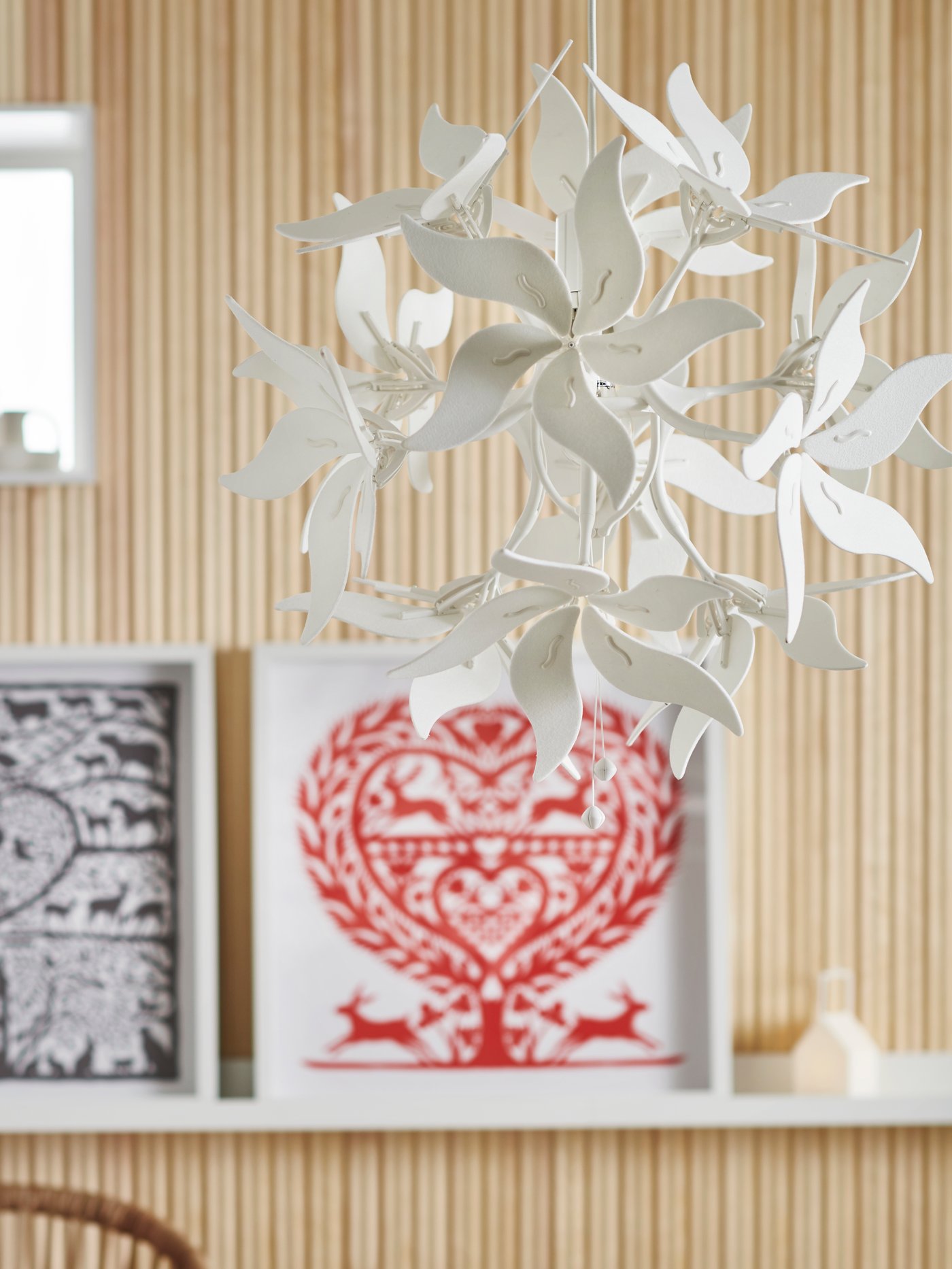 Detalle de una lámpara de techo blanca con forma geométrica, marcos blancos en un estante de pared blanco, objeto decorativo, en un salón.