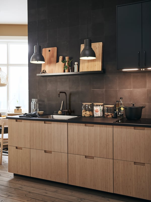 In this modern kitchen, FRÖJERED kitchen fronts in bamboo are paired with black tiled walls and accessories.