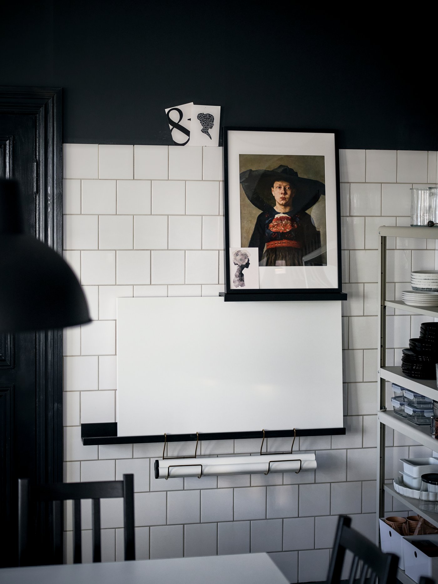Comedor con una silla marrón, una mesa, un cuadro enmarcado, un estante para cuadros con un panel blanco y un portarrollos de cocina.
