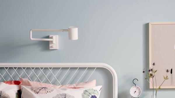 Una lámpara de pared NYMÅNE sobre una cama. 