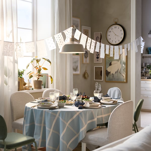 A bright dining room has a ROSENTORP extendable table that has been pulled out to accommodate five chairs and one highchair.