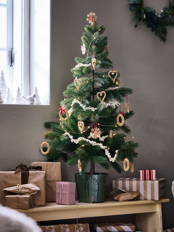 Un árbol de navidad VINTERFINT mediano sobre un butaco de madera.