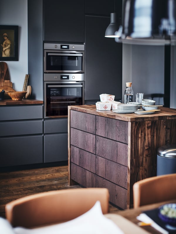 A METOD kitchen with a wooden kitchen island with plates and takeaway food containers on top.