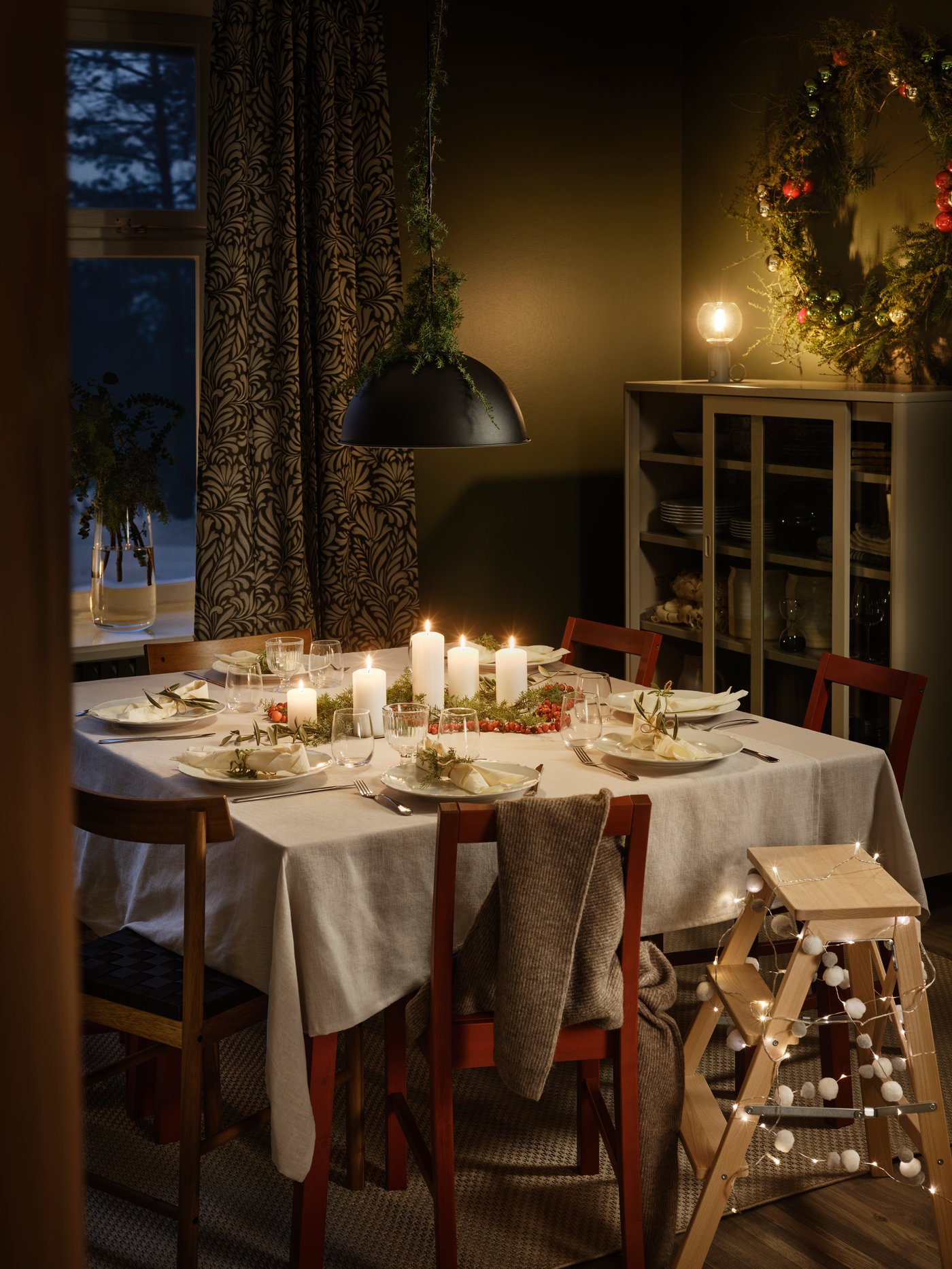 A room with a dining table in the middle. The table is set for Christmas gathering.