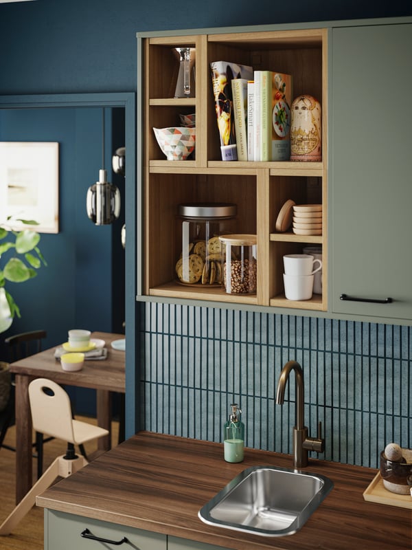 Una cocina en tonos turquesa con estantes de madera que sostienen frascos y accesorios.
