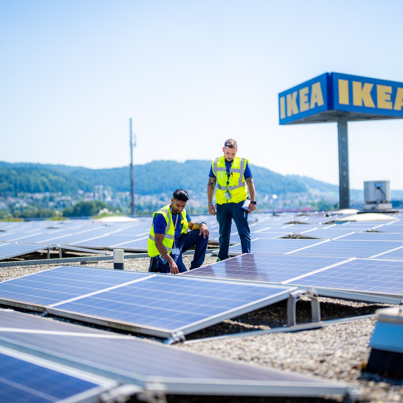 Solpaneler på taket av ett IKEA varuhus där två medarbetare inspekterar anläggningen.