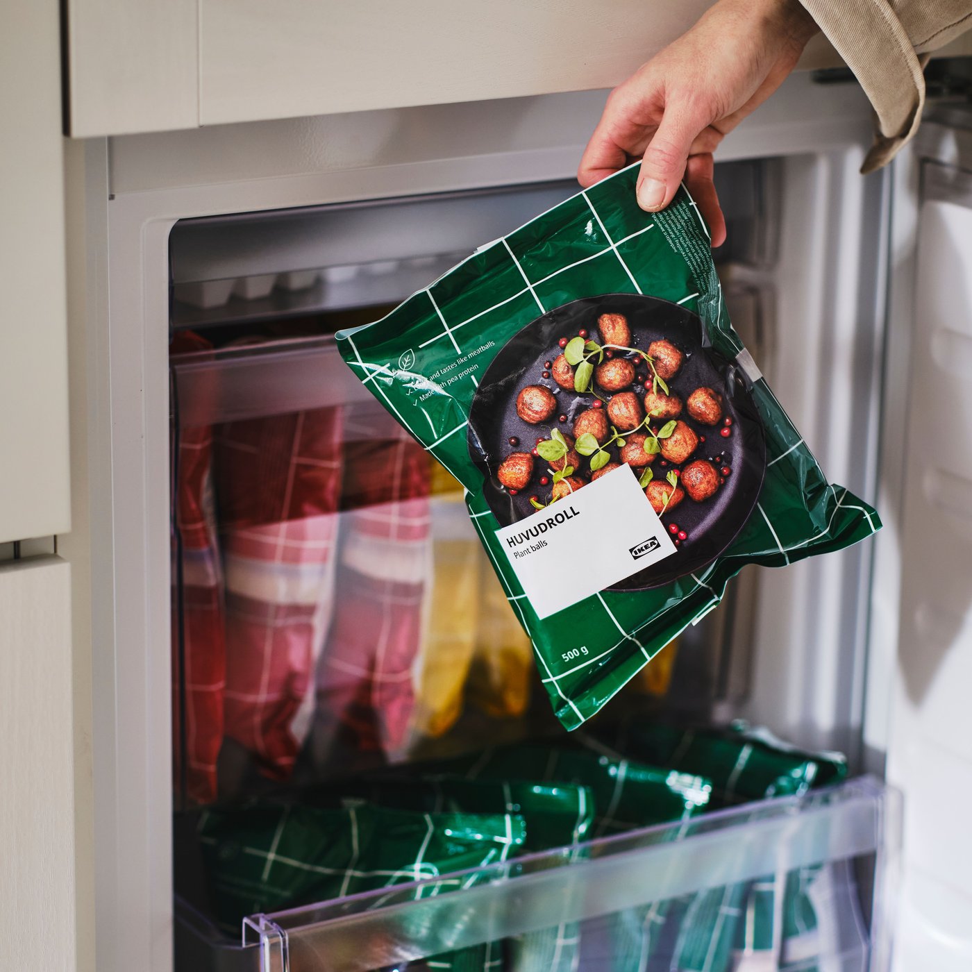 A hand pulls a bag of HUVUDROLL plant balls out of freezer.