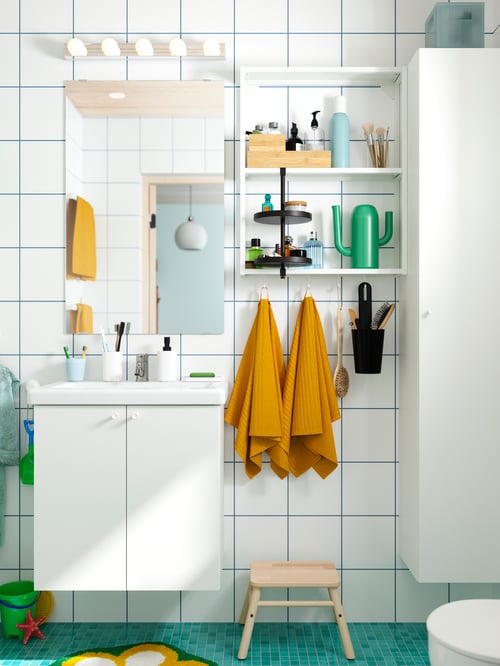 ENHET bathroom furniture set of 13, next to VÅGSJÖN bath towels, a step stool, and a green vase, in a modern bathroom.