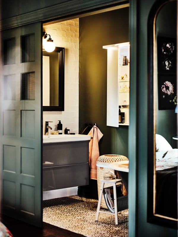 A bathroom with a black TOFTBYN mirror above a high-gloss grey/Dalskär tap GODMORGON wash-stand with two drawers.
