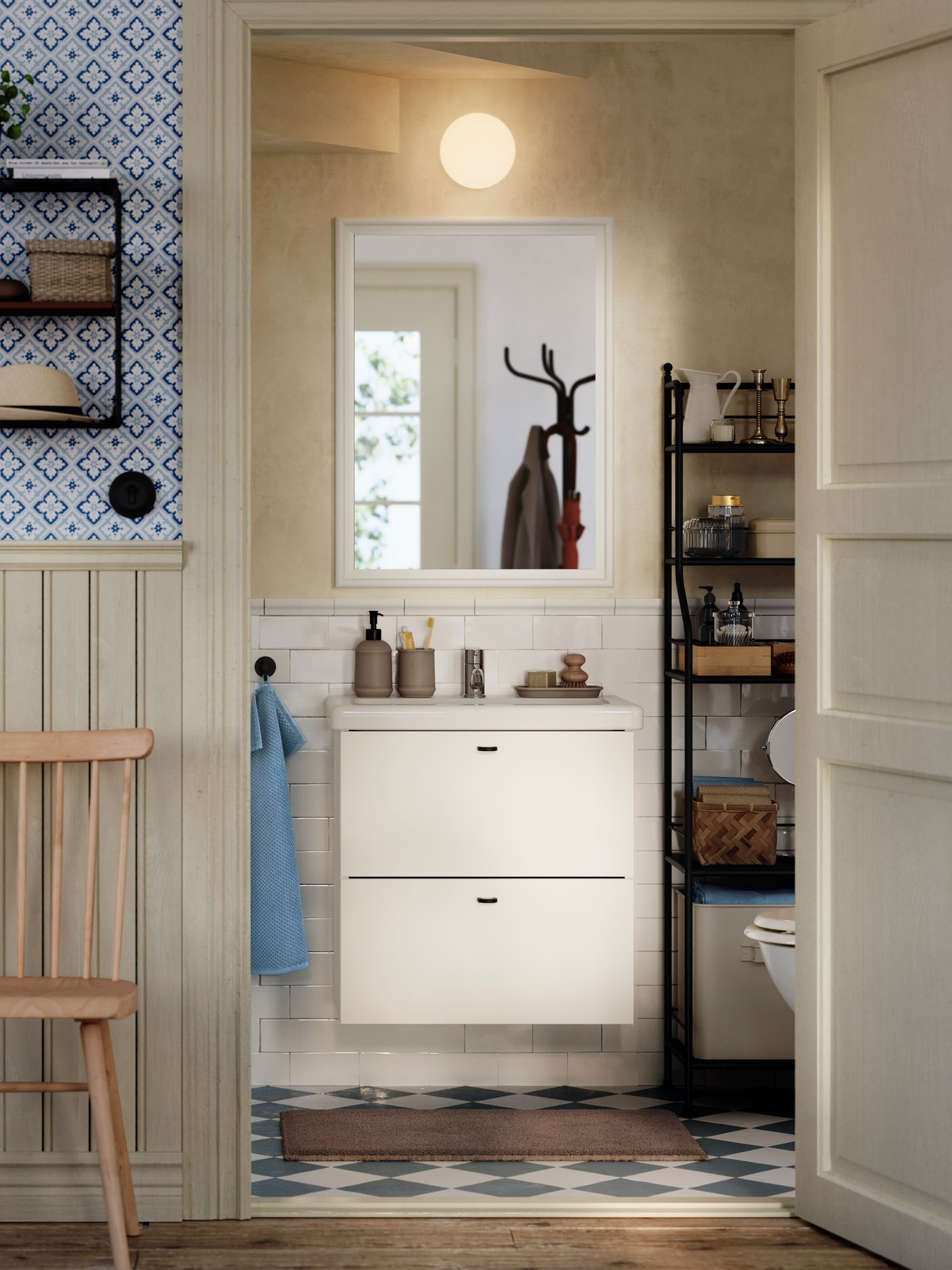 A white ENHET/TVÄLLEN wash-stand with drawers is on a subway-tiled wall in a traditional-styled half bath under a staircase.