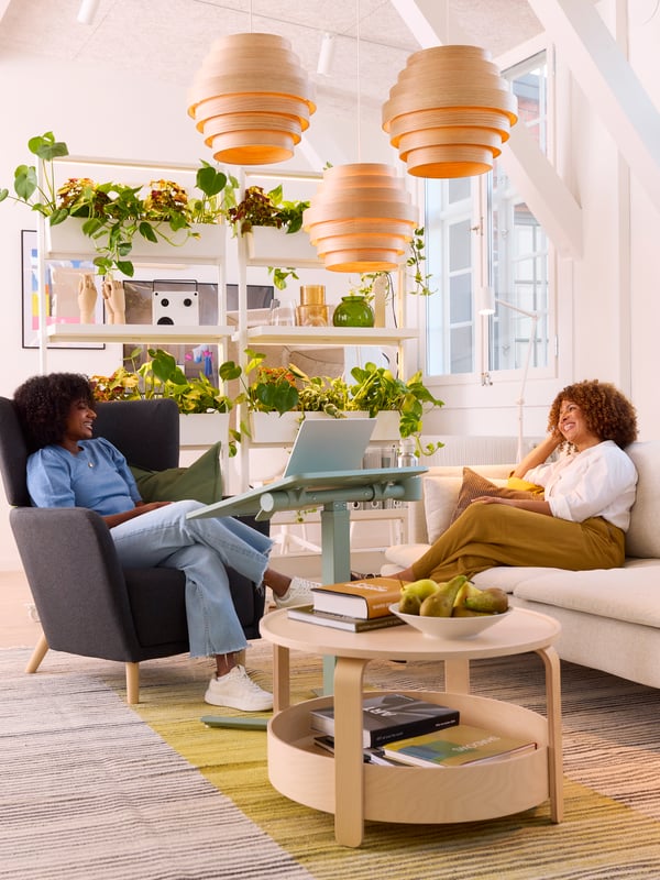 Two people are having a conversation while sitting on a couch and chair across from each other in an office.