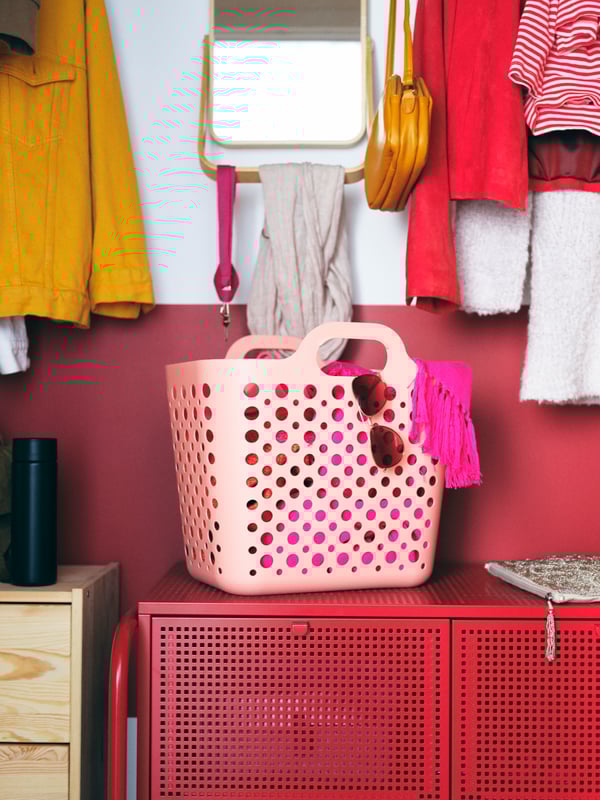 A corner of a room with three high, grey IVAR cabinets with mesh doors filled with clothes, and various boxes on top.