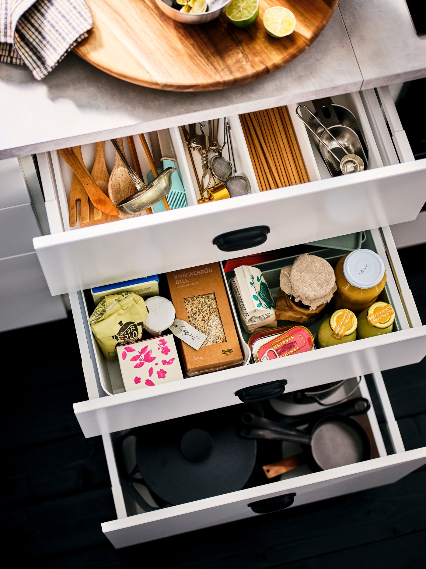 A column of drawn-out, white drawers, revealing neatly organised pantry-compatible bottles, jars and kitchen accessories.