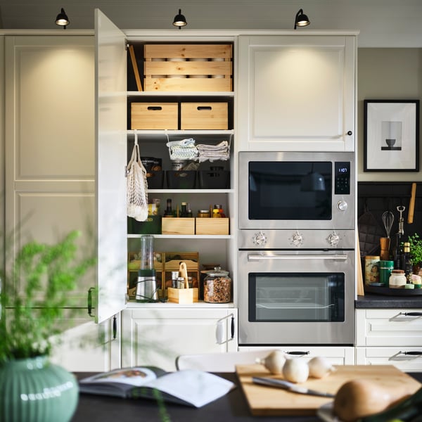 Ett modernt kök med ugn och mikrovågsugn i rostfritt stål, ett prydligt organiserat skåp med UPPDATERA förvaringslådor.