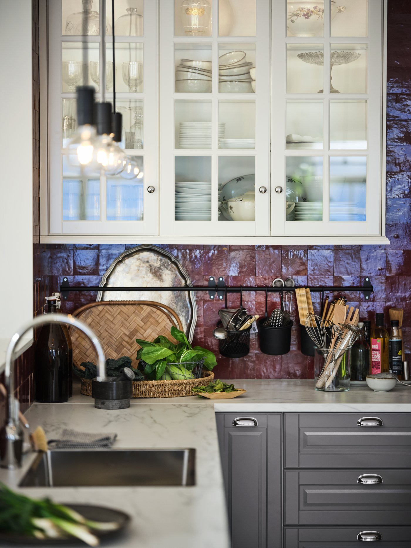 An EKBACKEN white-marble-effect worktop with METOD cabinets and MAXIMERA interiors in a red-tiled kitchen.