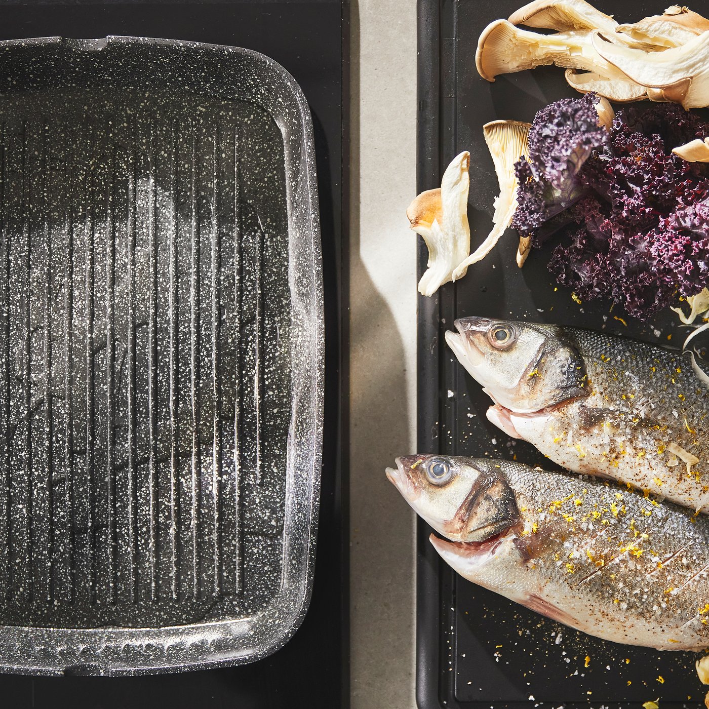 Una piastra HUSKNUT posta su un piano ad induzione con accanto del pesce 